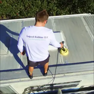 Person cleaning caravan roof with pressure washer