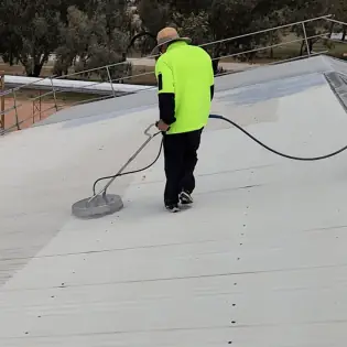Person pressure washing roof surface